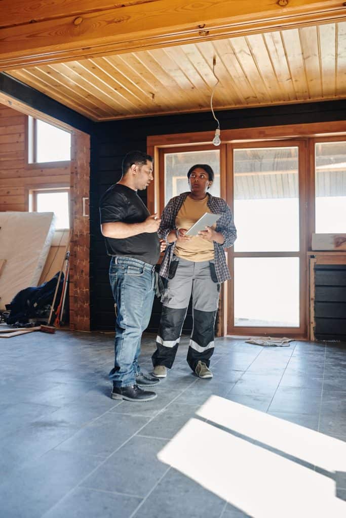 Contractor and homeowner reviewing a tablet together inside a home under repair